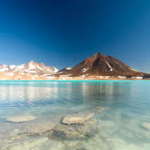 Lagon avec un volcan et des pics enneigés en arrière plan